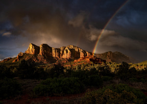 Небольшая горная цепь на фоне пасмурного неба и радуги